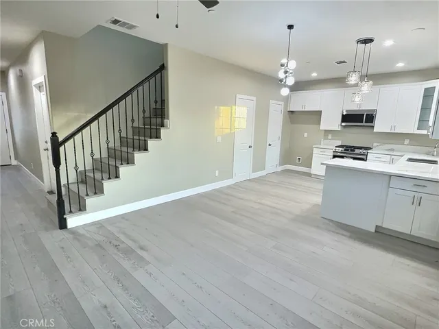 a view of a kitchen with a sink a refrigerator wooden floor and chandelier