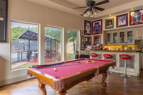 a room with pool table windows and wooden floor
