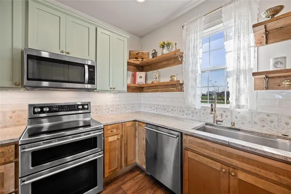a kitchen with stainless steel appliances granite countertop a stove a sink and a refrigerator with wooden floor