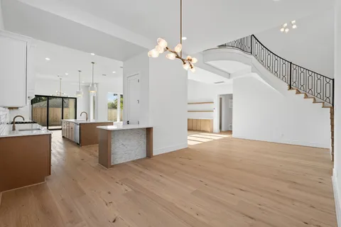 a view of an empty room with kitchen and window