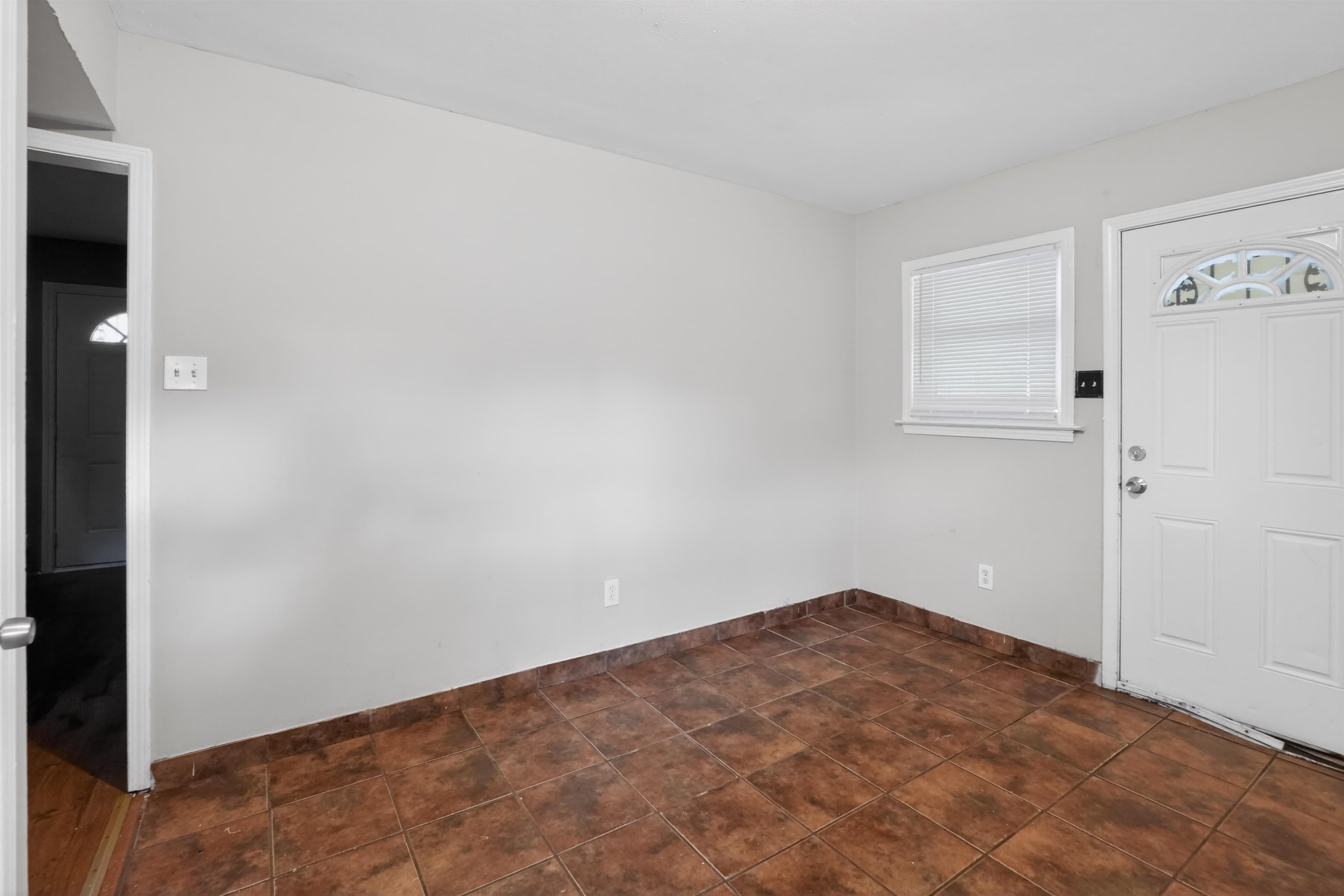 5124 Gill Road Memphis, TN 38109 - Photo 12 of 33 Neutral tone wall paint with a window and white blinds, complemented by a white paneled door with an arched glass insert