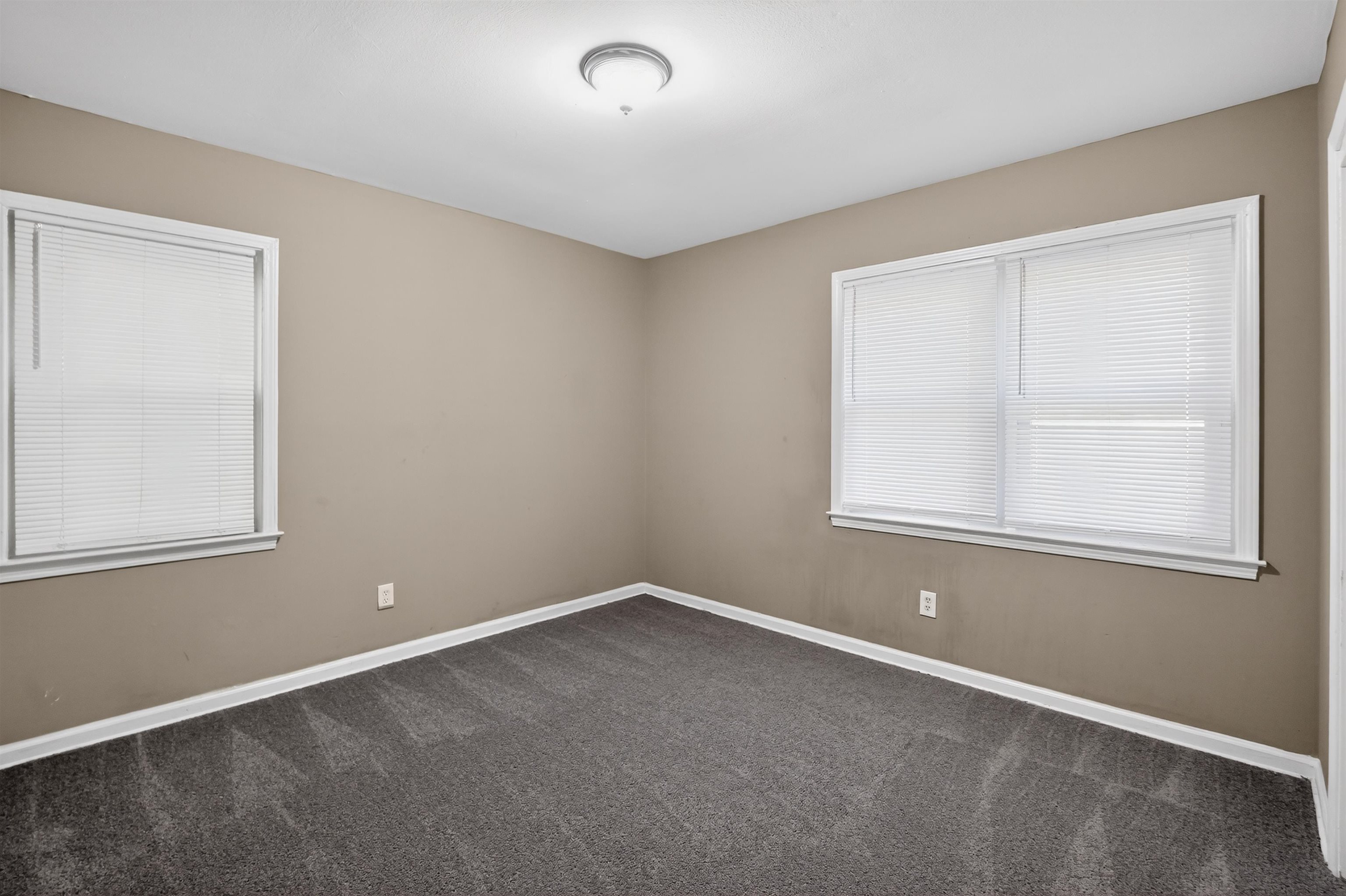 5124 Gill Road Memphis, TN 38109 - Photo 14 of 33 Neutral tone walls featuring two windows with white blinds, white trim, and dark gray carpet flooring