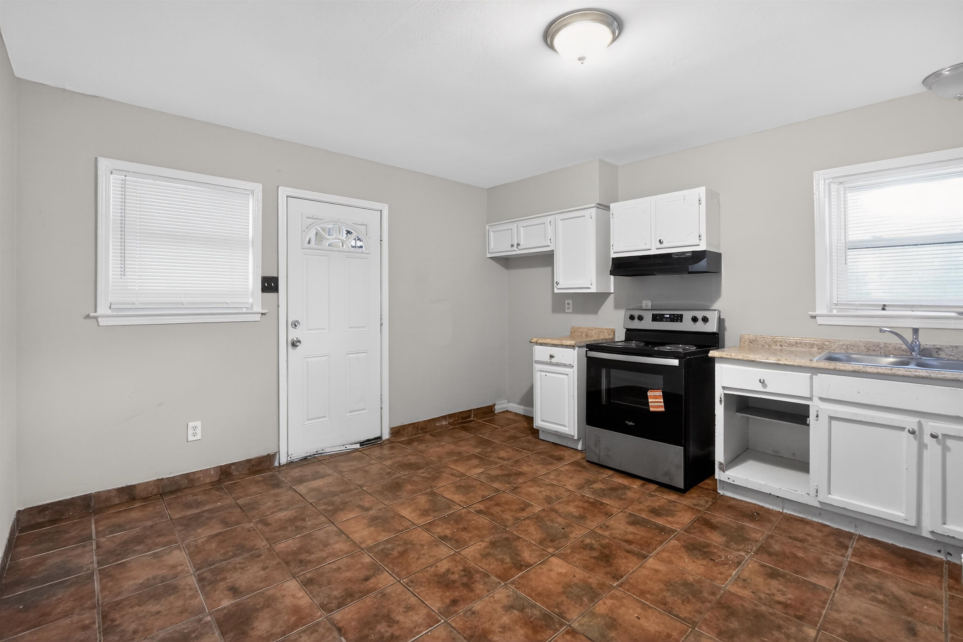 5124 Gill Road Memphis, TN 38109 - Photo 19 of 33 Kitchen area featuring ceramic tile flooring, white cabinetry, laminate countertops, a stainless steel and black range, and an overhead range hood