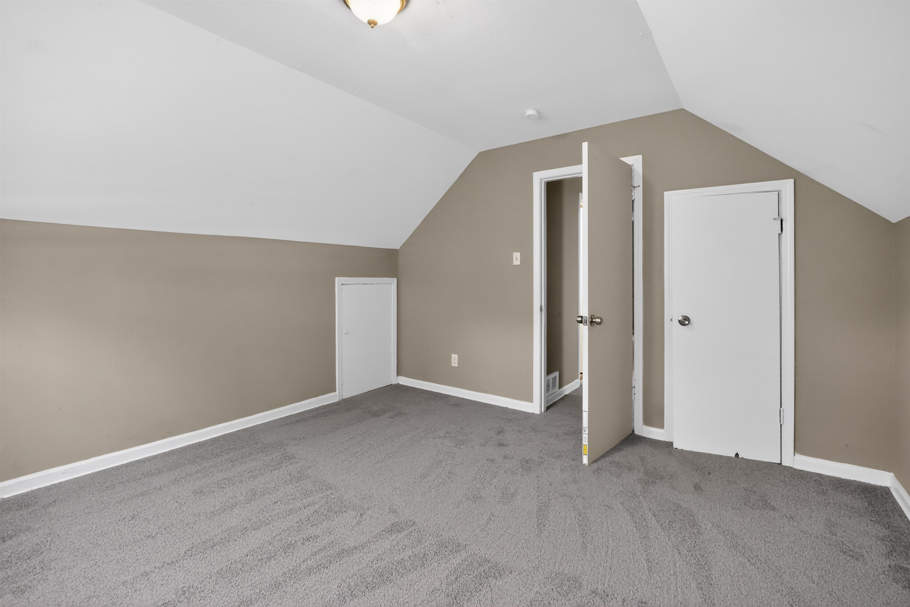 5124 Gill Road Memphis, TN 38109 - Photo 27 of 33 Carpeted room featuring a vaulted ceiling, neutral wall paint, white baseboards, and multiple white doors