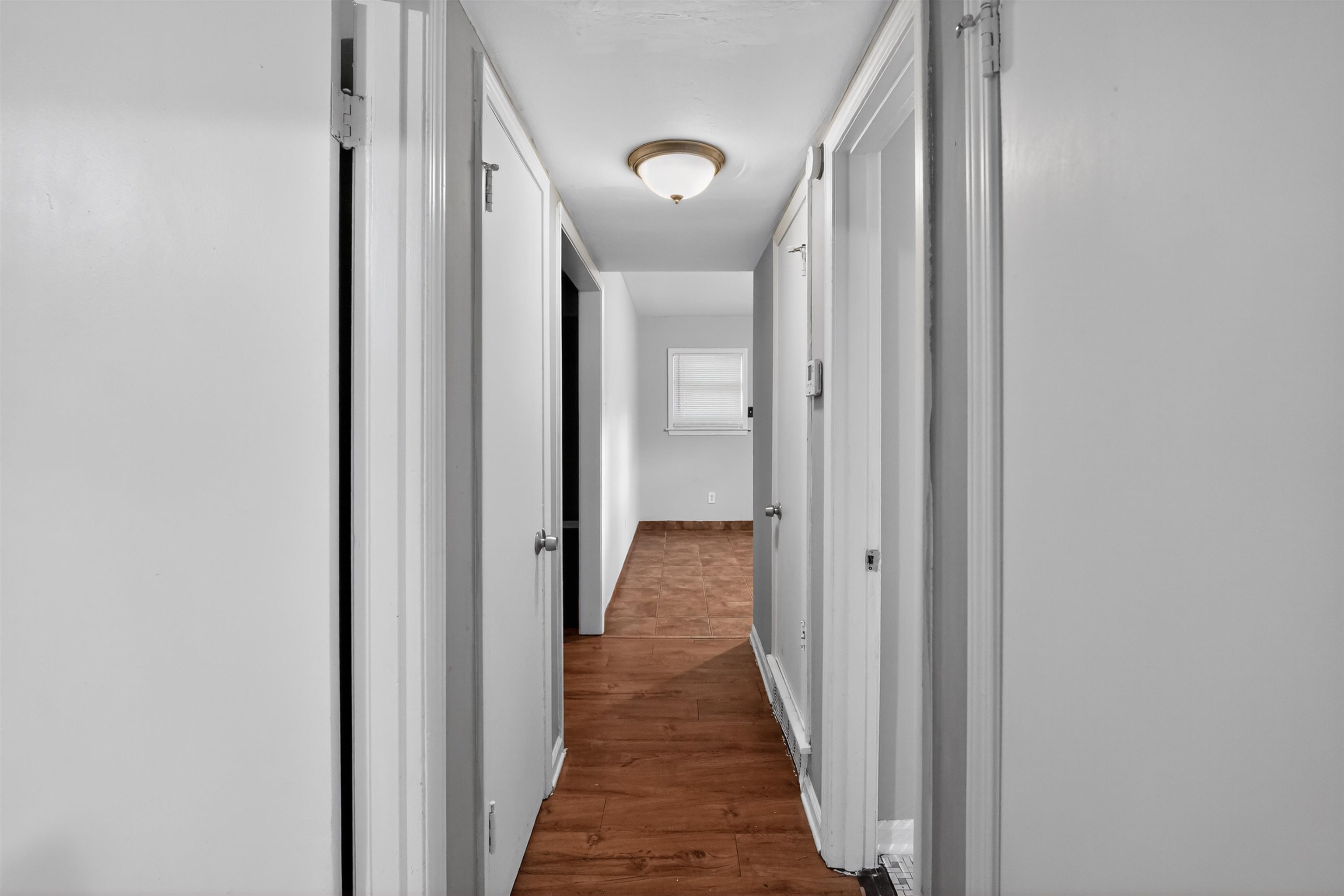 5124 Gill Road Memphis, TN 38109 - Photo 28 of 33 Hallway with wood-finish flooring, white walls, and a ceiling-mounted light fixture