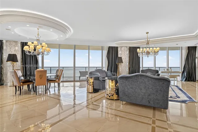 a view of a dining room with furniture a chandelier and large windows