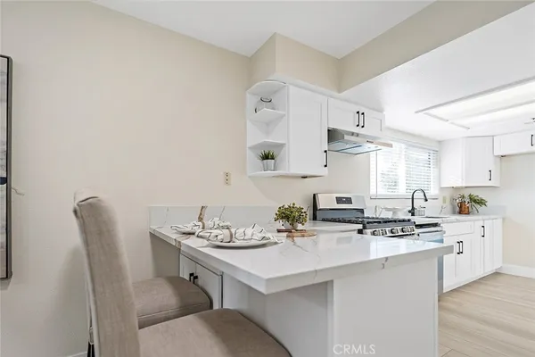 a kitchen with stainless steel appliances a sink a stove a table and chairs