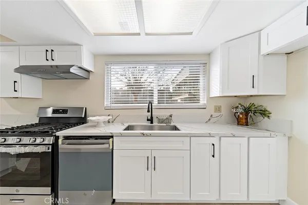 a kitchen with stainless steel appliances granite countertop a sink a stove and cabinets