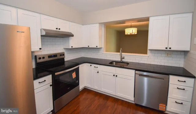 a kitchen with granite countertop white cabinets and stainless steel appliances