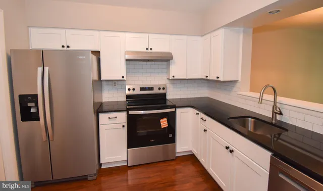 a kitchen with granite countertop a refrigerator sink and cabinets