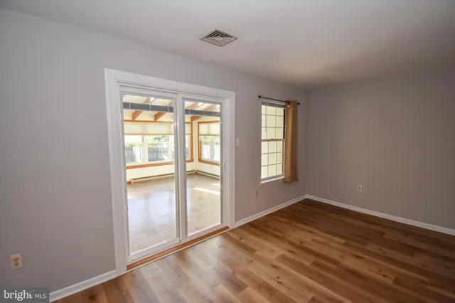 an empty room with wooden floor and windows
