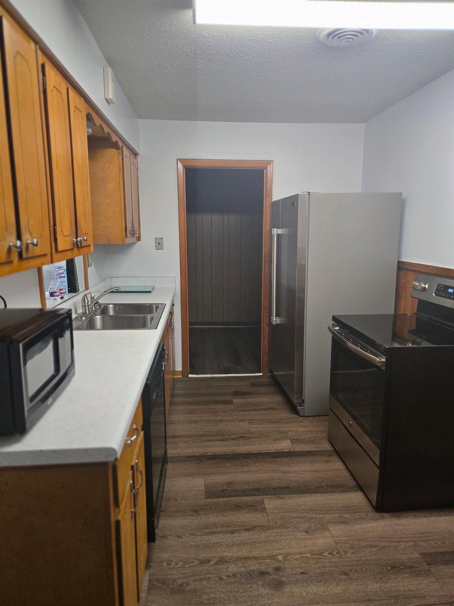 6855 Raleigh Lagrange Road Memphis, TN 38134 - Photo 7 of 13 Kitchen featuring brown cabinetry, black appliances, a textured ceiling, light countertops, and dark wood-style floors