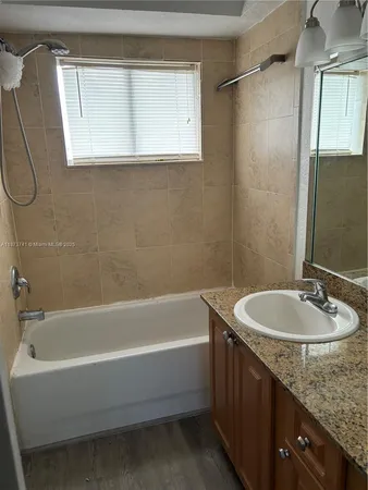 a bathroom with a granite countertop sink and a bathtub