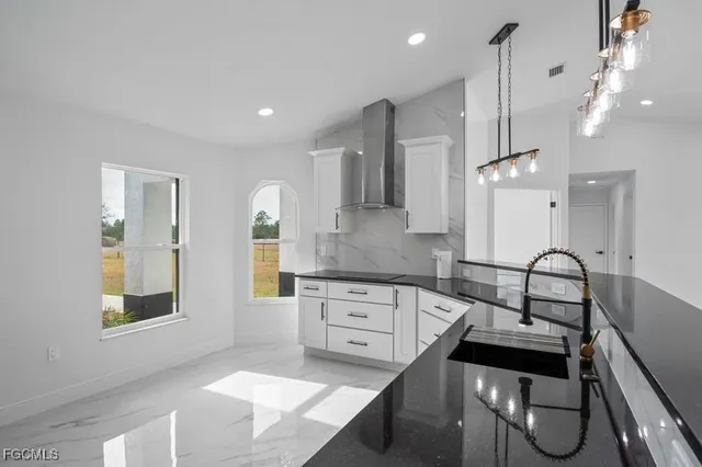 a kitchen with granite countertop a stove a sink a dining table and chairs