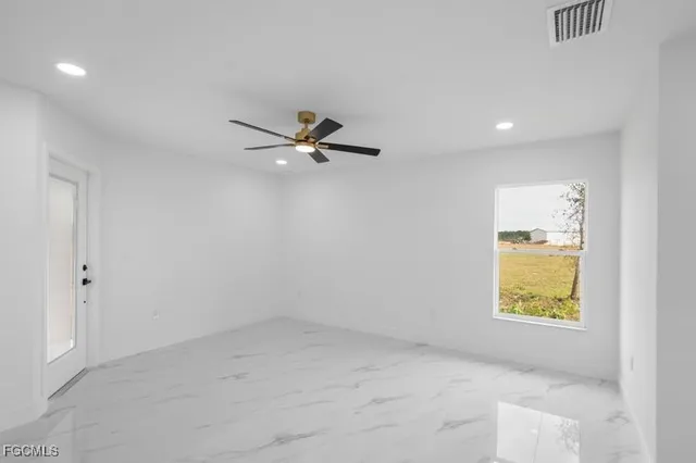an empty room with a window and a ceiling fan