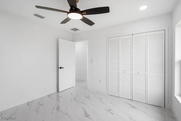 an empty room with ceiling fan and windows