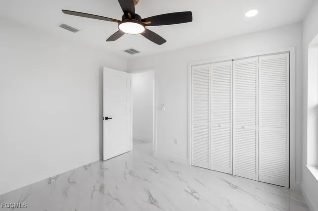 an empty room with ceiling fan and windows