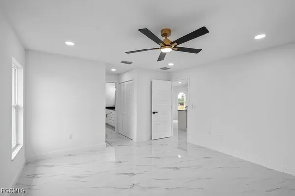 an empty room with windows and fan