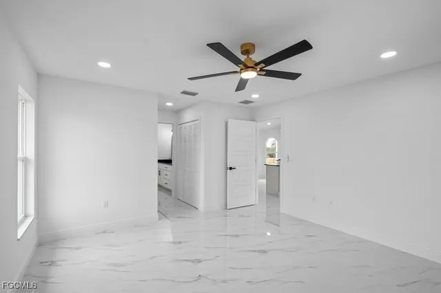 an empty room with windows and fan