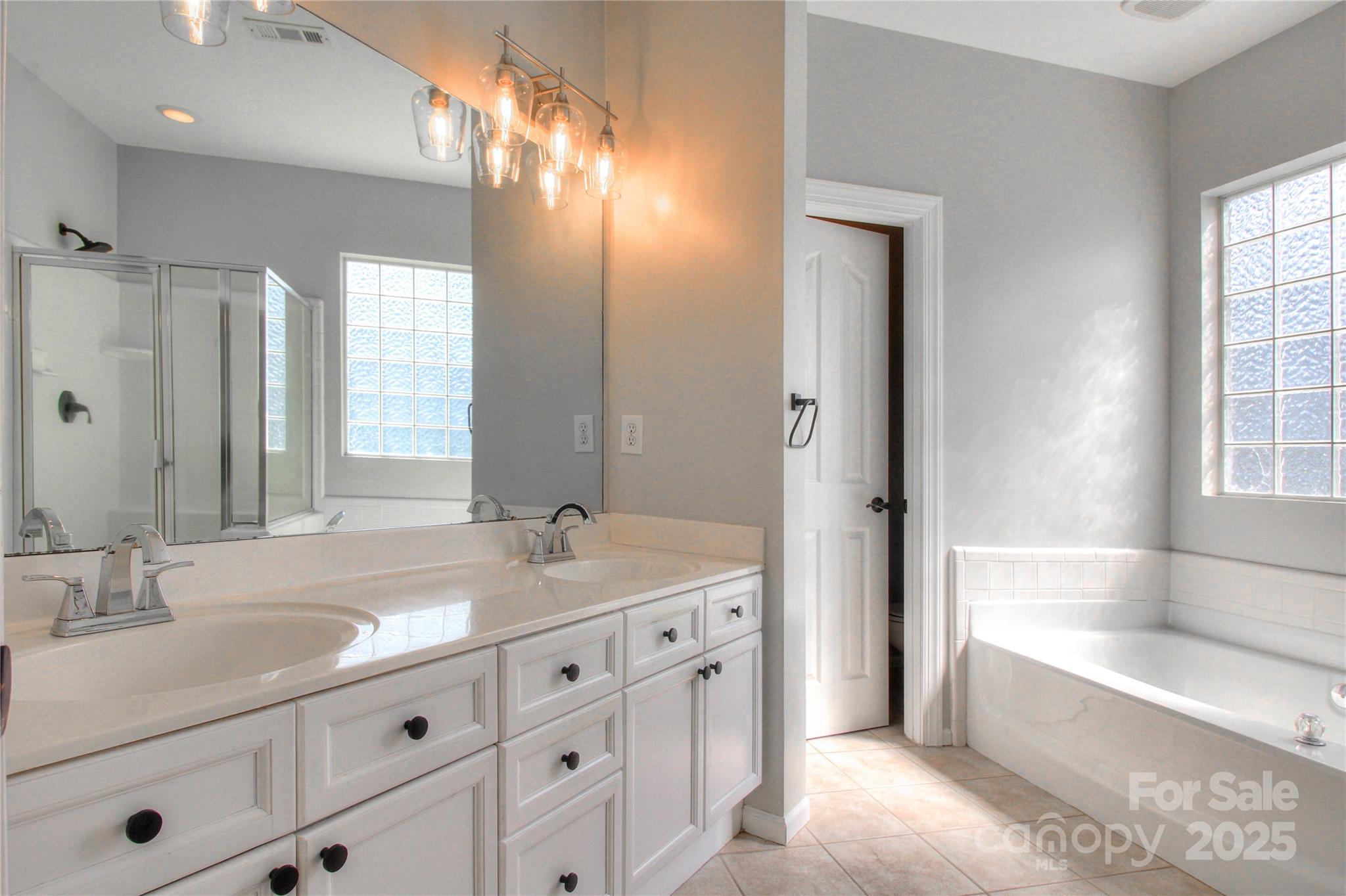 8414 Bampton Drive Concord, NC 28027 - Photo 20 of 32 a bathroom with a sink double vanity granite tub shower and a mirror