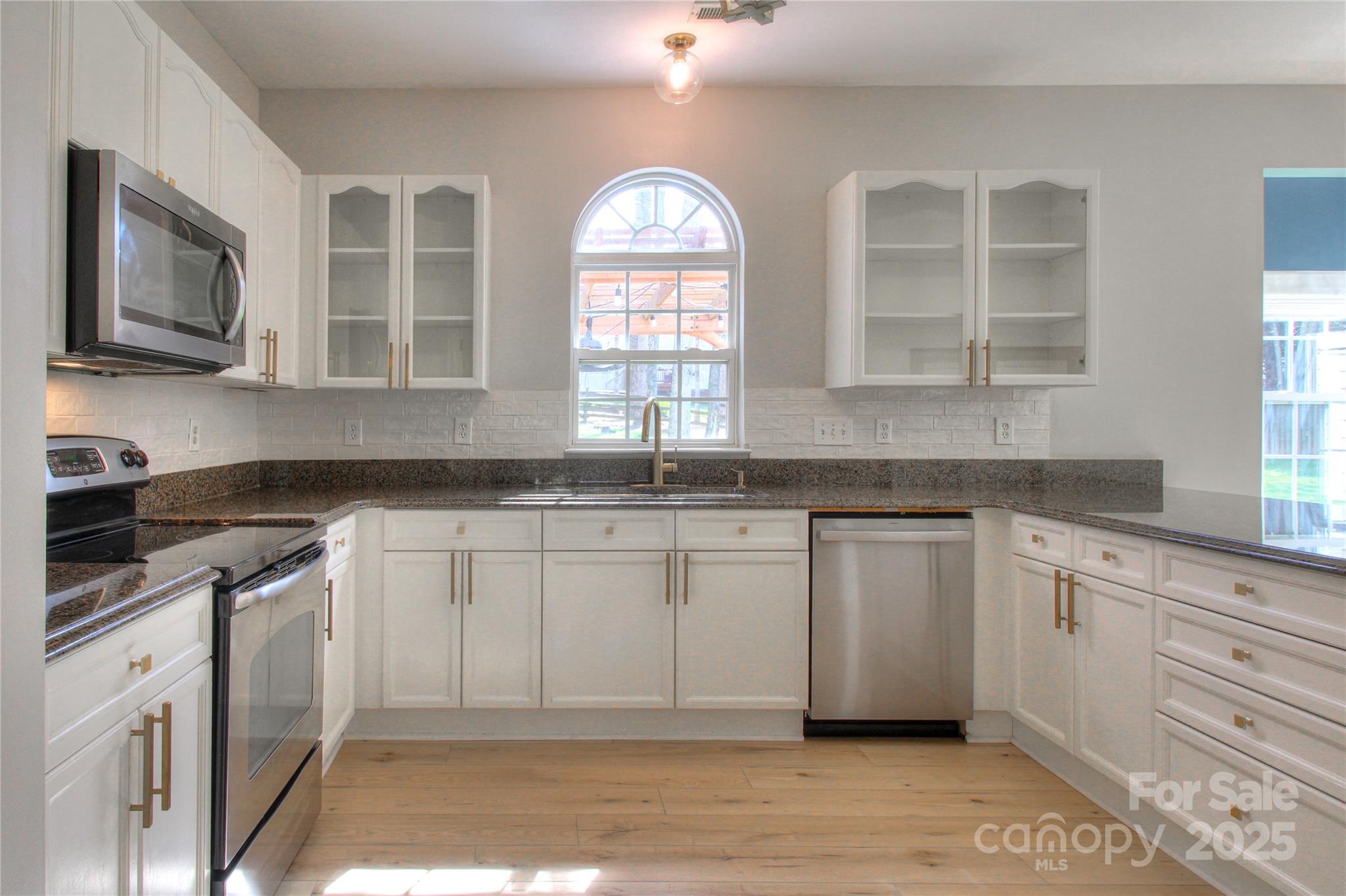 8414 Bampton Drive Concord, NC 28027 - Photo 2 of 32 a kitchen with granite countertop a stove a sink and a microwave