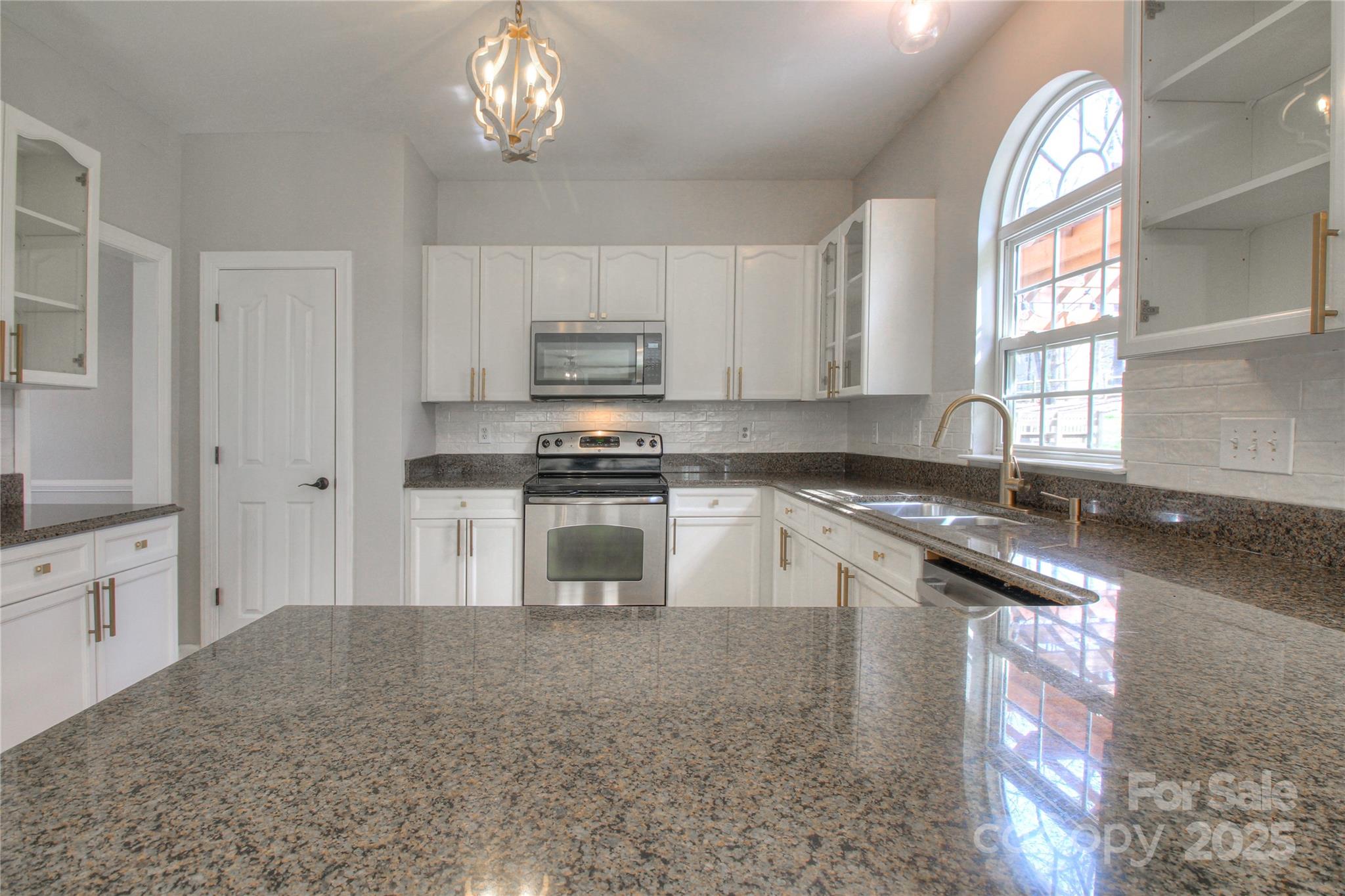 8414 Bampton Drive Concord, NC 28027 - Photo 3 of 32 a kitchen with kitchen island granite countertop a stove sink and cabinets