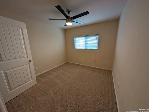 an empty room with a ceiling fan and window