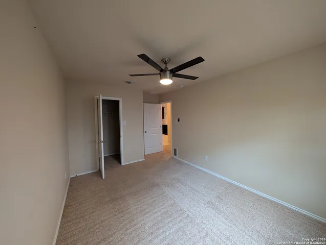 an empty room with closet and ceiling fan