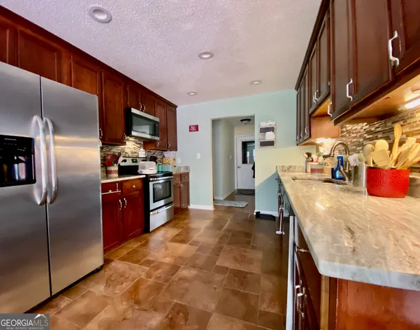 a kitchen with stainless steel appliances granite countertop a sink a stove and a refrigerator