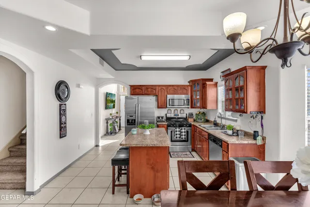 a kitchen with stainless steel appliances granite countertop a stove top oven a sink a dining table and chairs with white cabinets