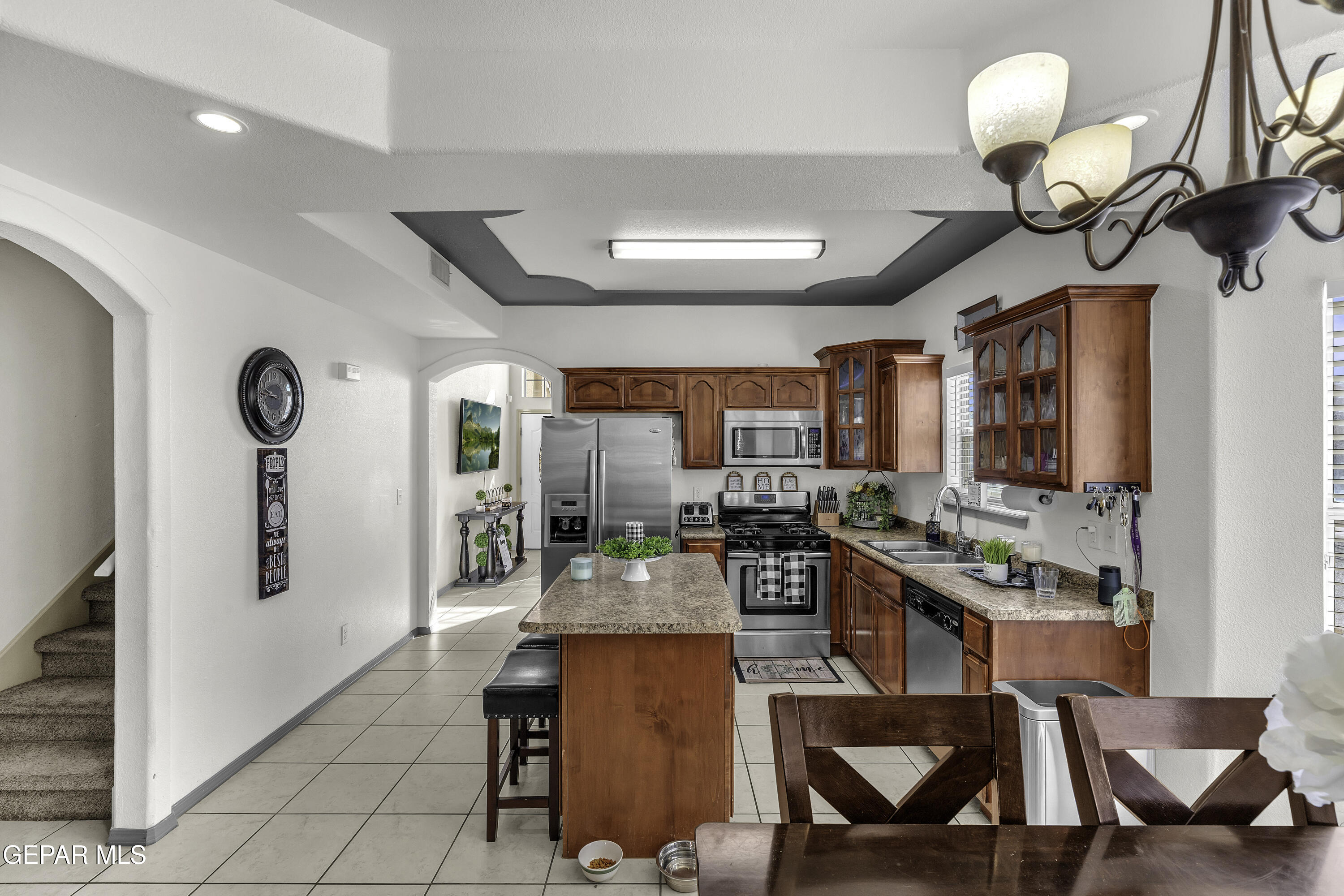 14401 Delta Point Court El Paso, TX 79938 - Photo 22 of 49 a kitchen with stainless steel appliances granite countertop a stove top oven a sink a dining table and chairs with white cabinets