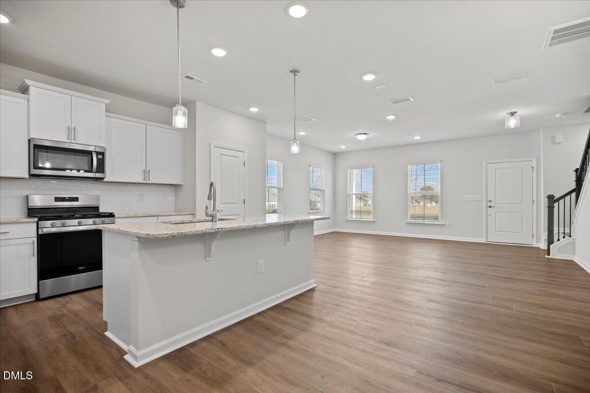 373 Fosterton Cottage Way Raleigh, NC 27603 - Photo 8 of 42 a large kitchen with stainless steel appliances granite countertop a stove a sink dishwasher and a microwave oven with wooden floor