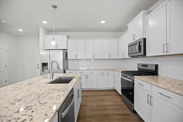 a large kitchen with stainless steel appliances granite countertop a stove a sink dishwasher and a microwave oven with wooden floor