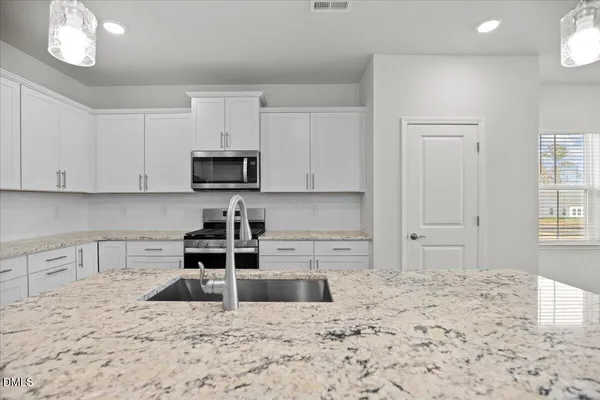 a kitchen with stainless steel appliances granite countertop a sink refrigerator and microwave