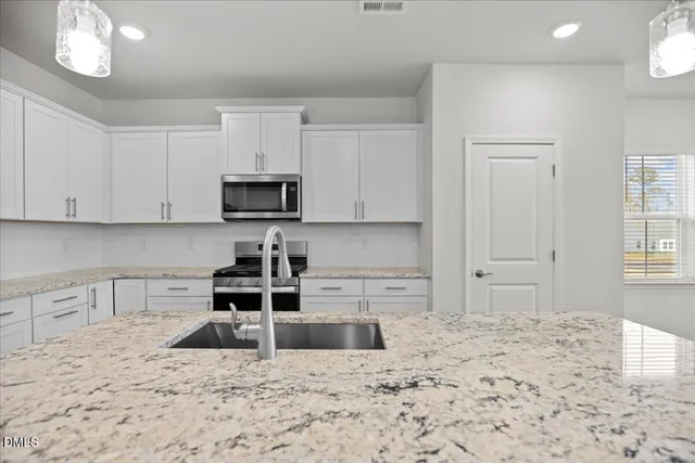 a kitchen with stainless steel appliances granite countertop a sink refrigerator and microwave