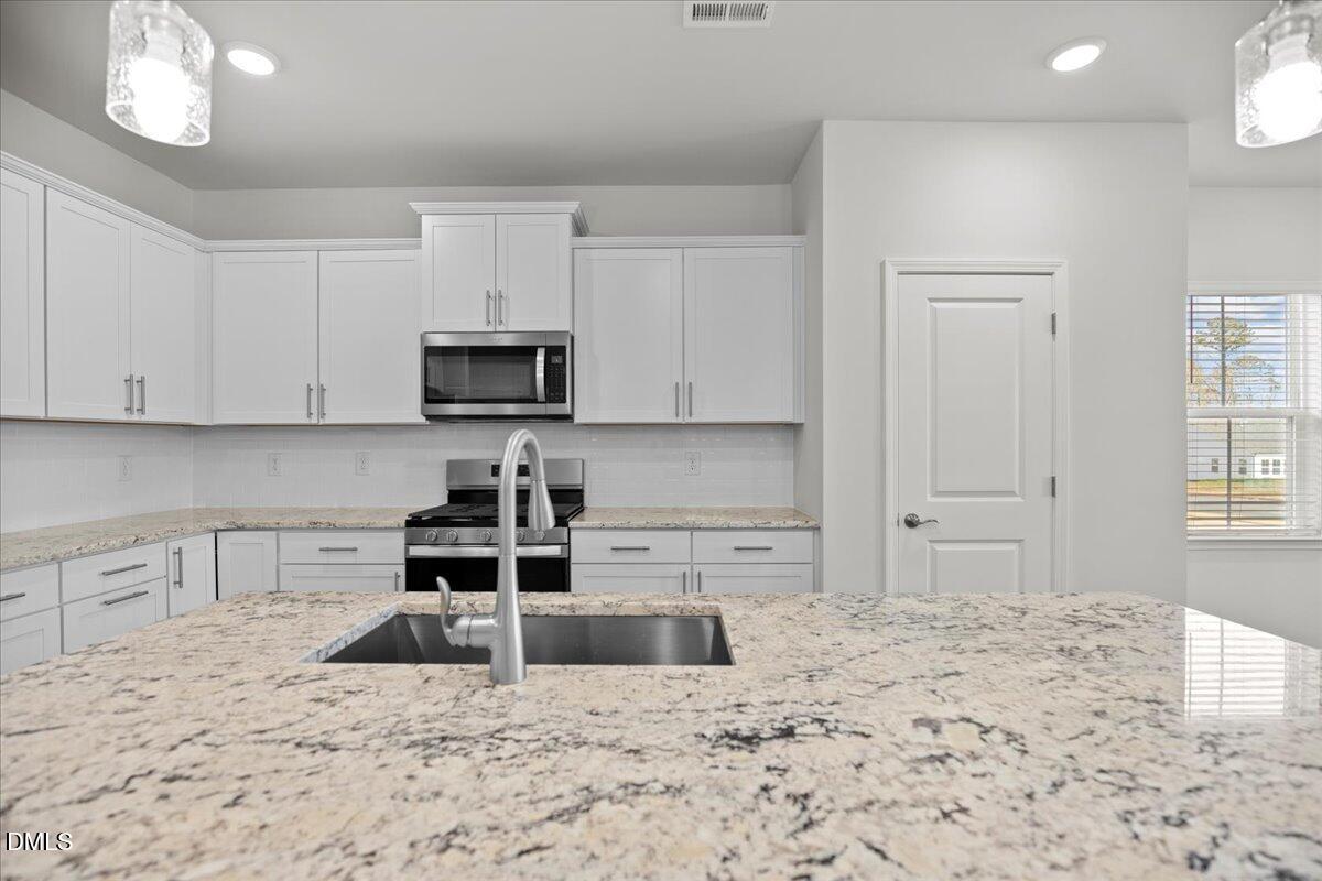 373 Fosterton Cottage Way Raleigh, NC 27603 - Photo 13 of 42 a kitchen with a stove a sink and a white cabinets