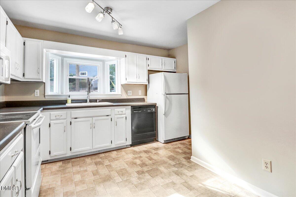 5738 3 Oaks Drive Raleigh, NC 27612 - Photo 6 of 32 a kitchen with white cabinets and white appliances
