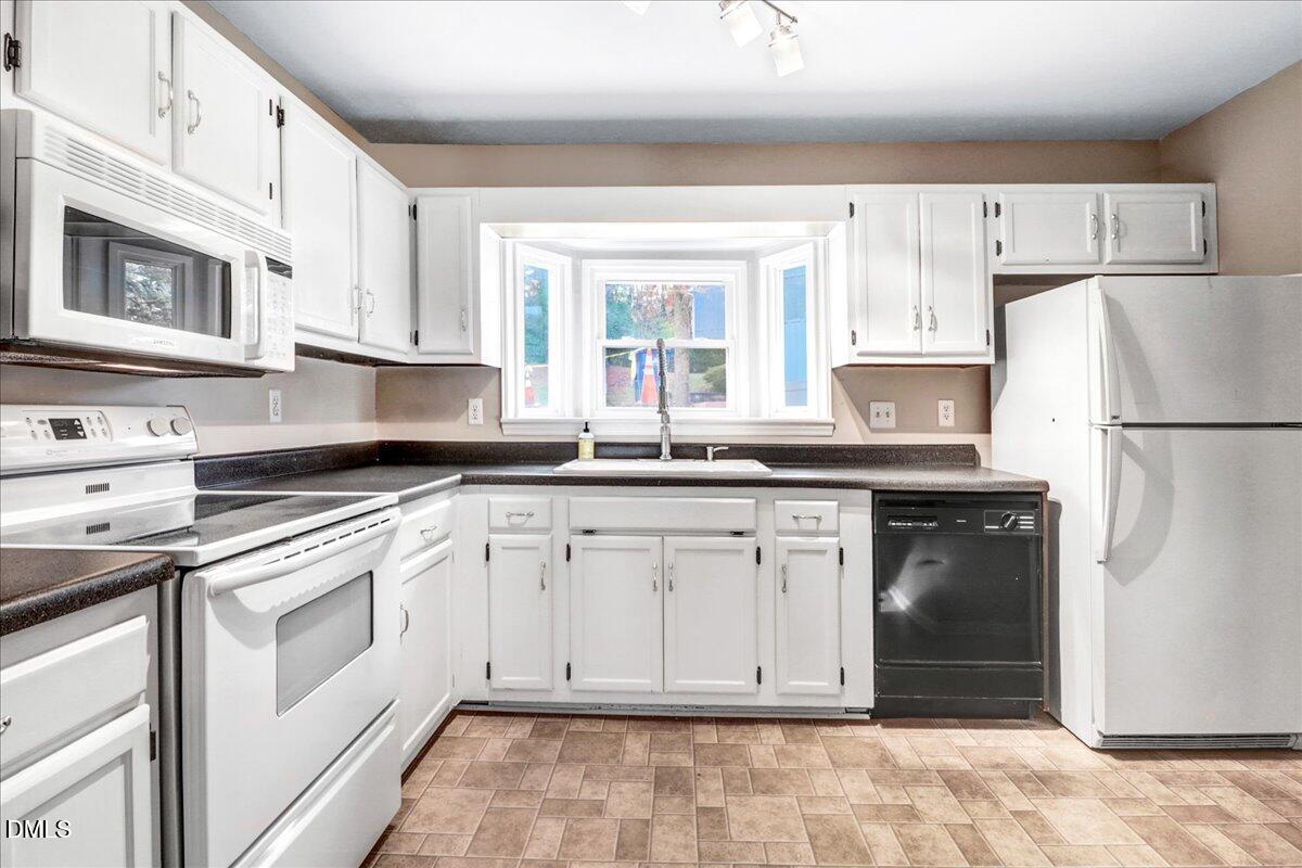 5738 3 Oaks Drive Raleigh, NC 27612 - Photo 7 of 32 a kitchen with granite countertop white cabinets white appliances and sink
