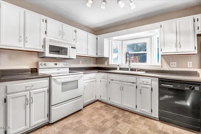a kitchen with granite countertop white cabinets white appliances and sink