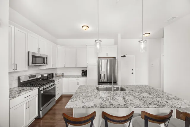 a kitchen with stainless steel appliances granite countertop a stove a sink and a refrigerator