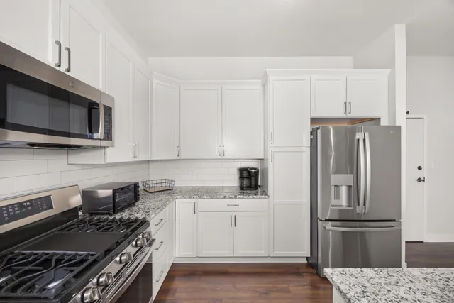 a kitchen with stainless steel appliances white cabinets and a stove top oven