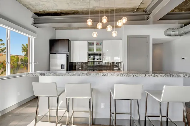 a kitchen with stainless steel appliances granite countertop a sink and a refrigerator