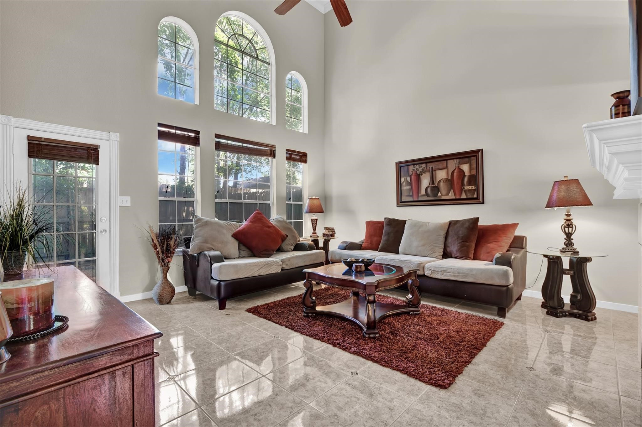 14420 Walters Road, Unit 16 Houston, TX 77014 - Photo 7 of 27 This spacious living room features high ceilings and large arched windows that flood the space with natural light. It includes a cozy seating area with a modern sectional sofa, accent pillows, and a stylish coffee table on a plush area rug. The room is elegantly decorated with warm tones and art pieces, creating an inviting atmosphere.