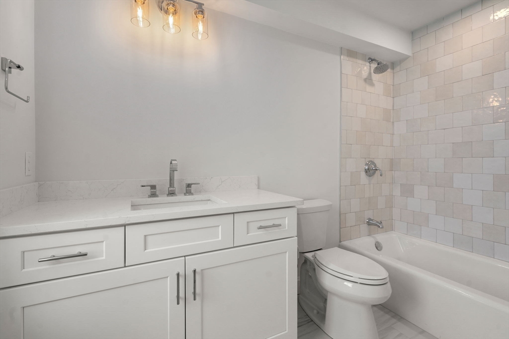 97 Bacon Street, Unit B Natick, MA 01760 - Photo 11 of 37 a bathroom with a toilet a sink a mirror a shower and vanity