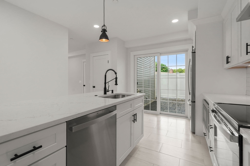 97 Bacon Street, Unit B Natick, MA 01760 - Photo 8 of 37 a kitchen with a sink stove and cabinets