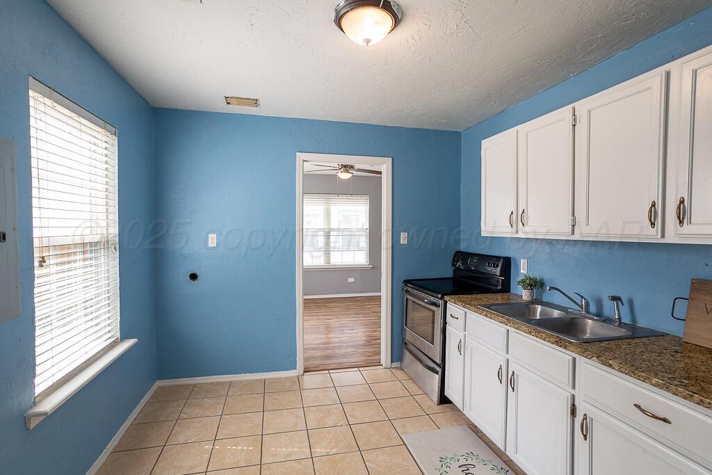 4105 Gables Street Amarillo, TX 79110 - Photo 7 of 18 a kitchen with granite countertop a sink a stove cabinets and a window