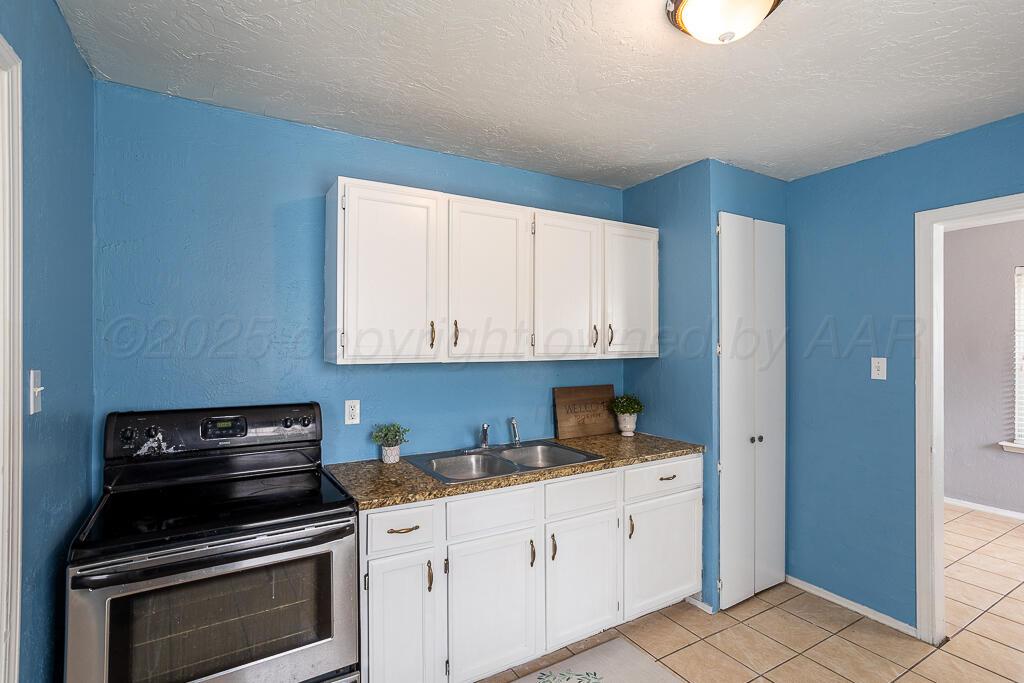 4105 Gables Street Amarillo, TX 79110 - Photo 8 of 18 a kitchen with white cabinets and black appliances