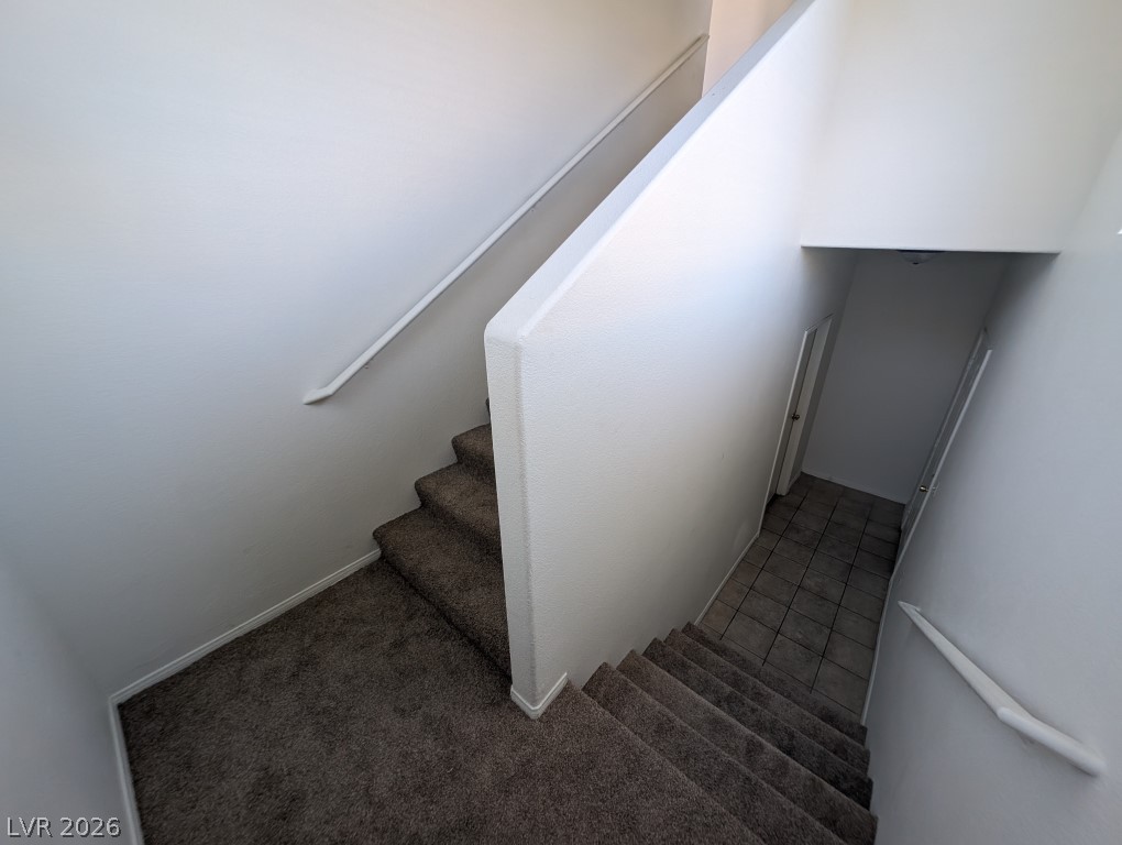 10550 West Alexander Road, Unit 2117 Las Vegas, NV 89129 - Photo 3 of 24 Clean lines and neutral carpeting define this multi-level staircase leading to a tiled entry.
