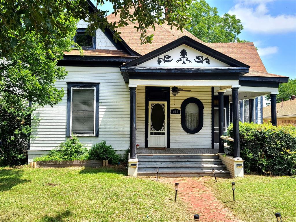 View of front of house featuring covered porch, a front yard, and roof with shingles