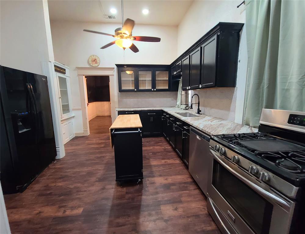 615 West Gandy Street Denison, TX 75020 - Photo 11 of 20 Kitchen with stainless steel appliances, dark cabinets, a ceiling fan, a center island, and glass insert cabinets